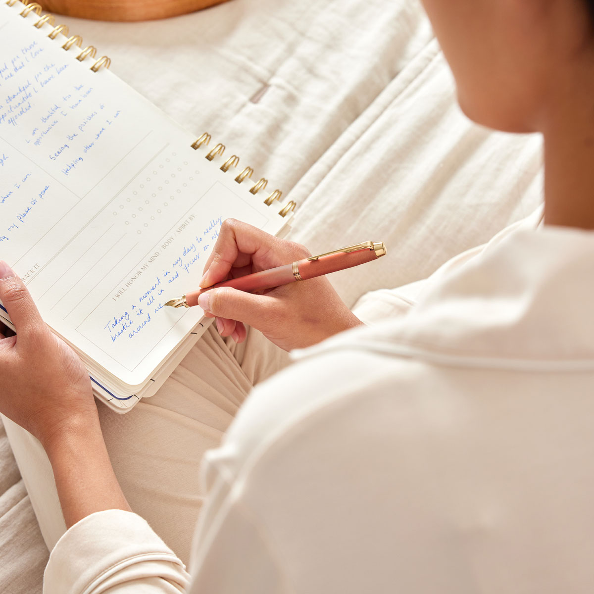 Kobieta pisząca piórem Parker IM Rituals Uplifting Orange GT w plannerze – scena codziennego rytuału pisania i refleksji.